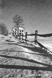 35mm black & white  photo taken in Franklin Township, NJ of an historic farmhouse after a snow storm. High contrast and shadows cast in the snow from a fence.