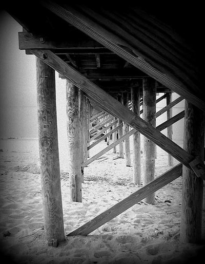    Faded black & white photo of under the Keansburg Beach, NJ, wood pier. Stylized with a geometric, abstract quality.