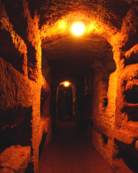 Mysterious photo of the catacomb tombs in Rome, Italy. Blacks and oranges. Underground burial site that is hundreds of years old. Dark walk way with tombs on the sides.