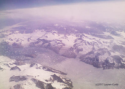 Areal view taken from an airplane of snow capped mountains of Greenland.
