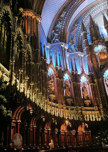 Ornate and Gothic architecture interior of Notre Dame cathedral in Montreal, Canada. Tall organ, flying buttresses, stained glass, statuary, religious art.